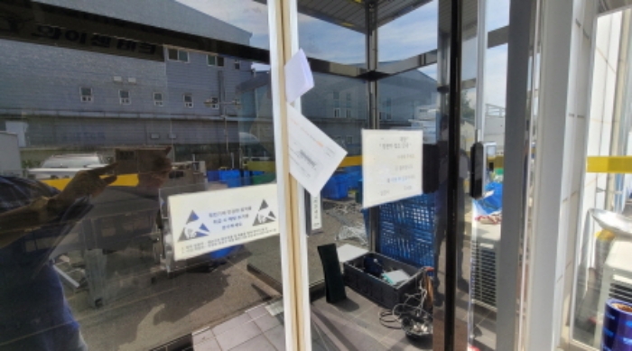 폐문된 공장건물 전면 출입구의 출입문(경매안내부 부착함)