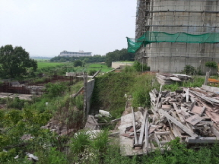 목록2 전경(공사중인 건물일부가 본건 대지에 들어와 있고,나대지엔 건축자재들이 흩어져 있음)