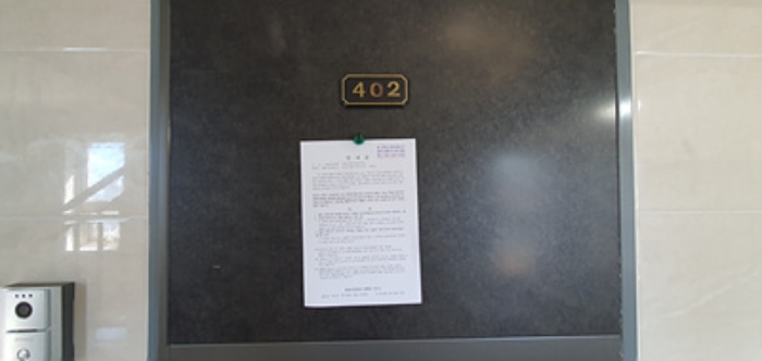 402호의 출입문에 부동산경매 사건에 대한 안내문 부착