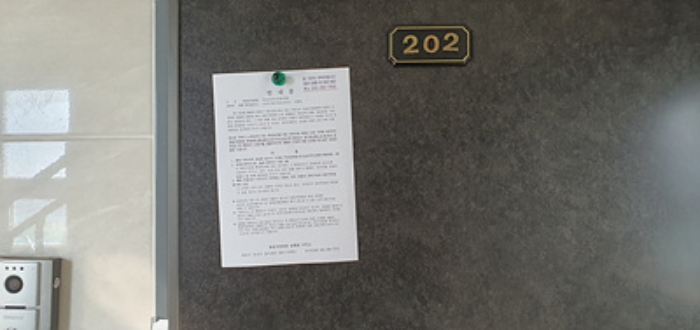 202호의 출입문에 부동산경매 사건에 대한 안내문 게시(8/6)