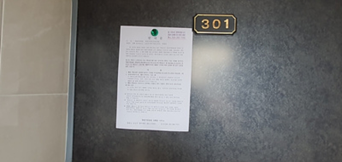 301호의 출입문에 부동산경매 사건에 대한 안내문 게시(8/6)