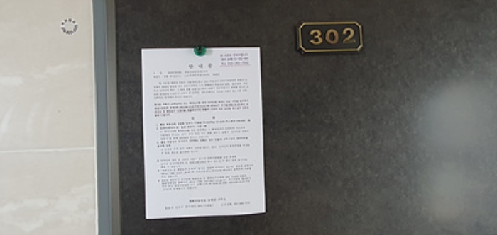 302호의 출입문에 부동산경매 사건에 대한 안내문 게시(8/6)