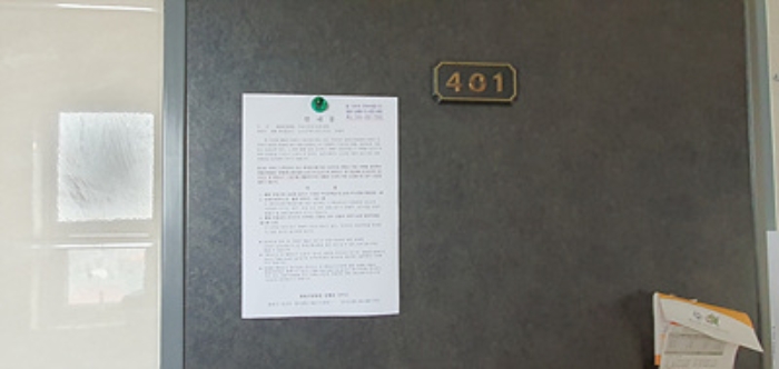 401호의 출입문에 부동산경매 사건에 대한 안내문 게시(8/6)