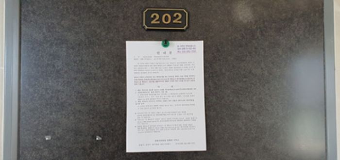 202호의 출입문에 부동산경매 사건에 대한 안내문 부착