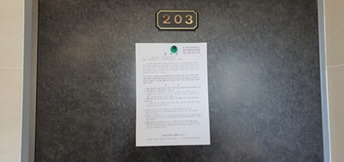 203호의 출입문에 부동산경매 사건에 대한 안내문 부착