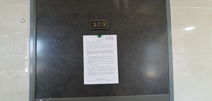 302호의 출입문에 부동산경매 사건에 대한 안내문 부착