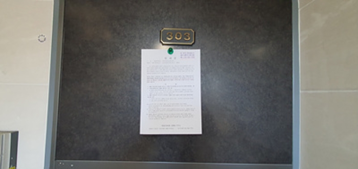 303호의 출입문에 부동산경매 사건에 대한 안내문 부착