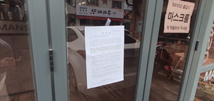 왼쪽 건물 출입문에 부동산경매 사건에 대한 안내문 부착