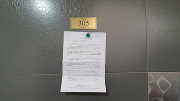 305호의 출입문에 부동산경매 사건에 대한 안내문 부착