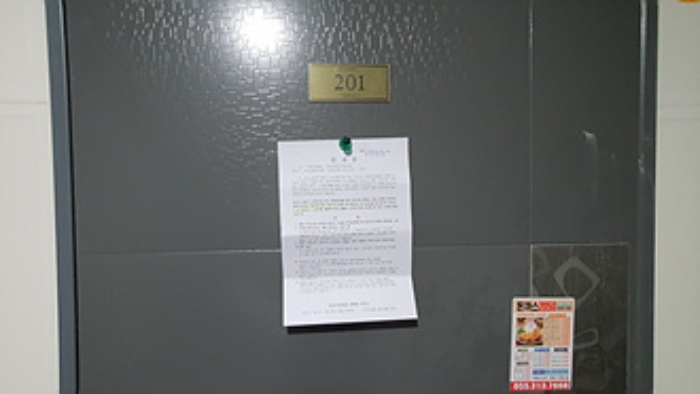 201호의 출입문에 부동산경매 사건에 대한 안내문 부착