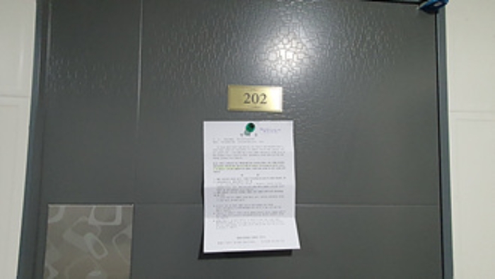 202호의 출입문에 부동산경매 사건에 대한 안내문 부착