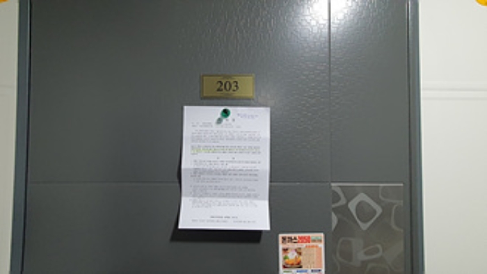 203호의 출입문에 부동산경매 사건에 대한 안내문 부착