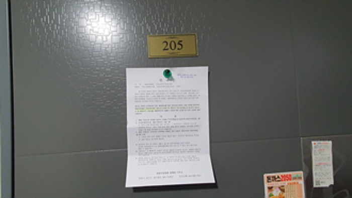 205호의 출입문에 부동산경매 사건에 대한 안내문 부착