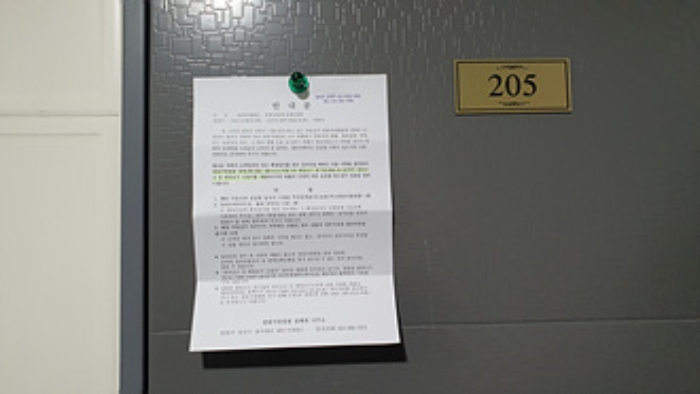 205호의 출입문에 부동산경매 사건에 대한 안내문 부착(1/4)
