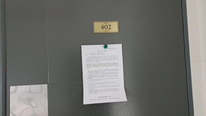 402호의 출입문에 부동산경매 사건에 대한 안내문 부착