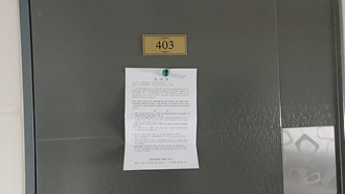 403호의 출입문에 부동산경매 사건에 대한 안내문 부착