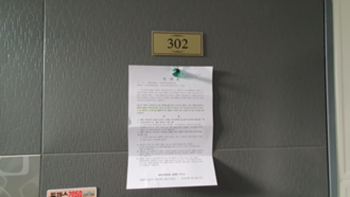 302호의 출입문에 부동산경매 사건에 대한 안내문 부착