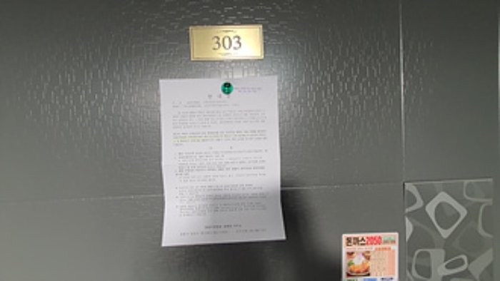 303호의 출입문에 부동산경매 사건에 대한 안내문 부착