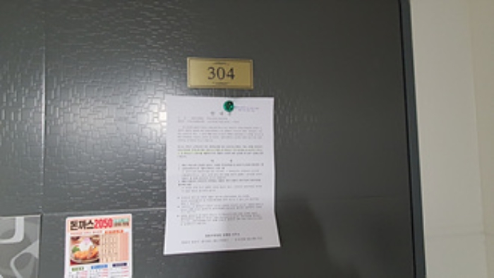 304호의 출입문에 부동산경매 사건에 대한 안내문 부착