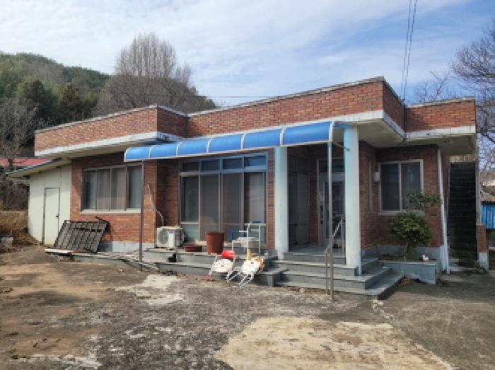 물건2, 주택 전면부 전경으로 전면부에 플라스틱 차양막 설치되어 있음.