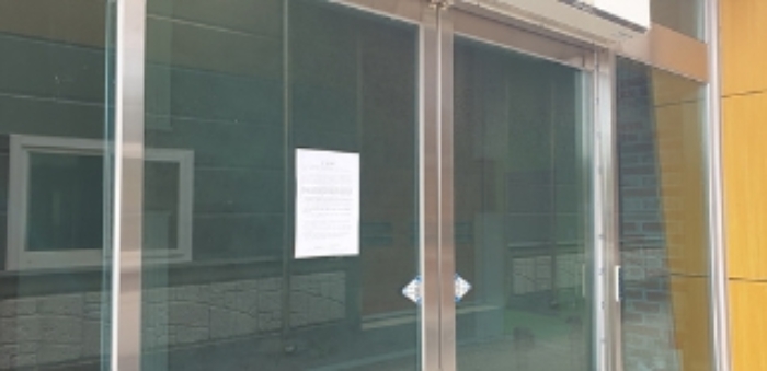 2번 부동산 건물 출입문 안내문 부착 모습