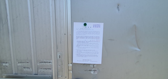 공장 입구문에 부동산경매 사건에 대한 안내문 부착
