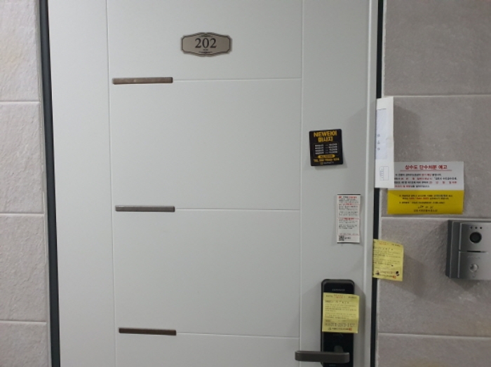 202호 현관문 (문 틈에 안내문을 끼워 둠)