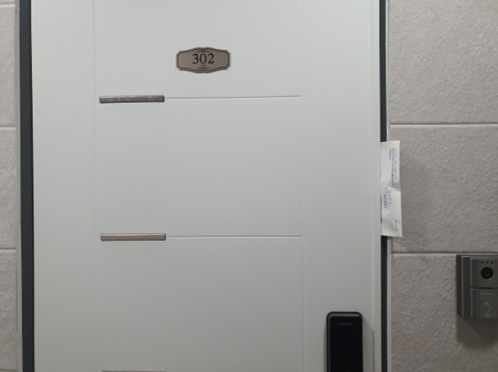 302호 현관문 (문 틈에 안내문을 끼워 둠)