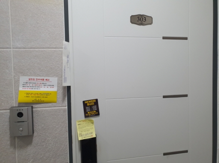303호 현관문 (문 틈에 안내문을 끼워 둠)