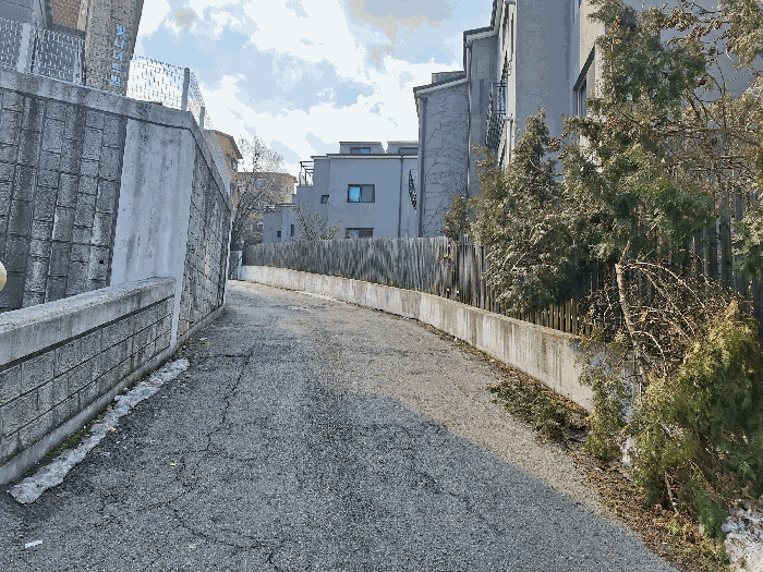 [본건 동측 도로(옹벽 우측이 본건 건물)]